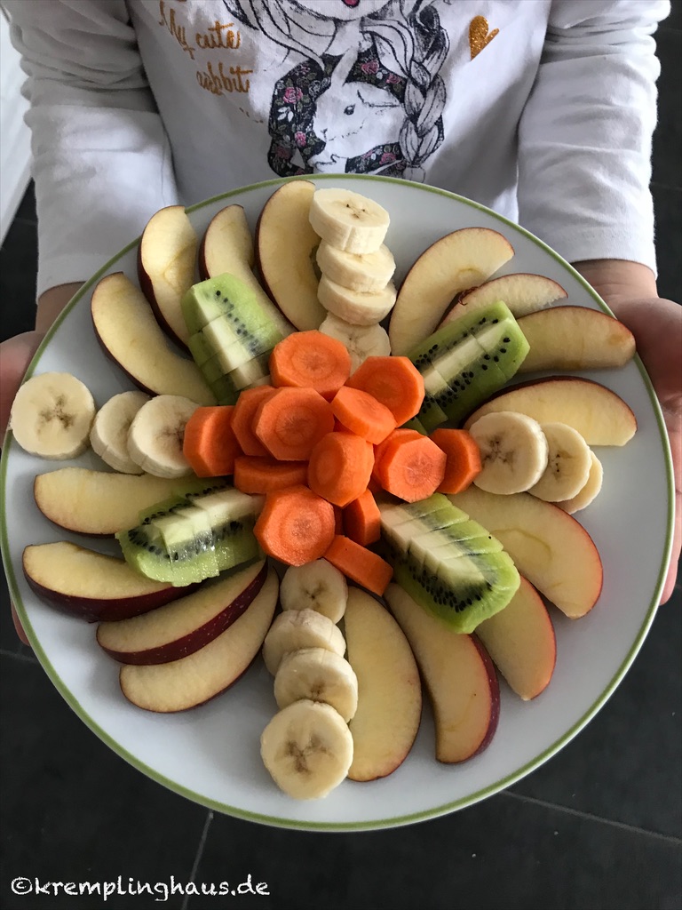 Obstteller mit Apfel, Banane, Kiwi und Möhre