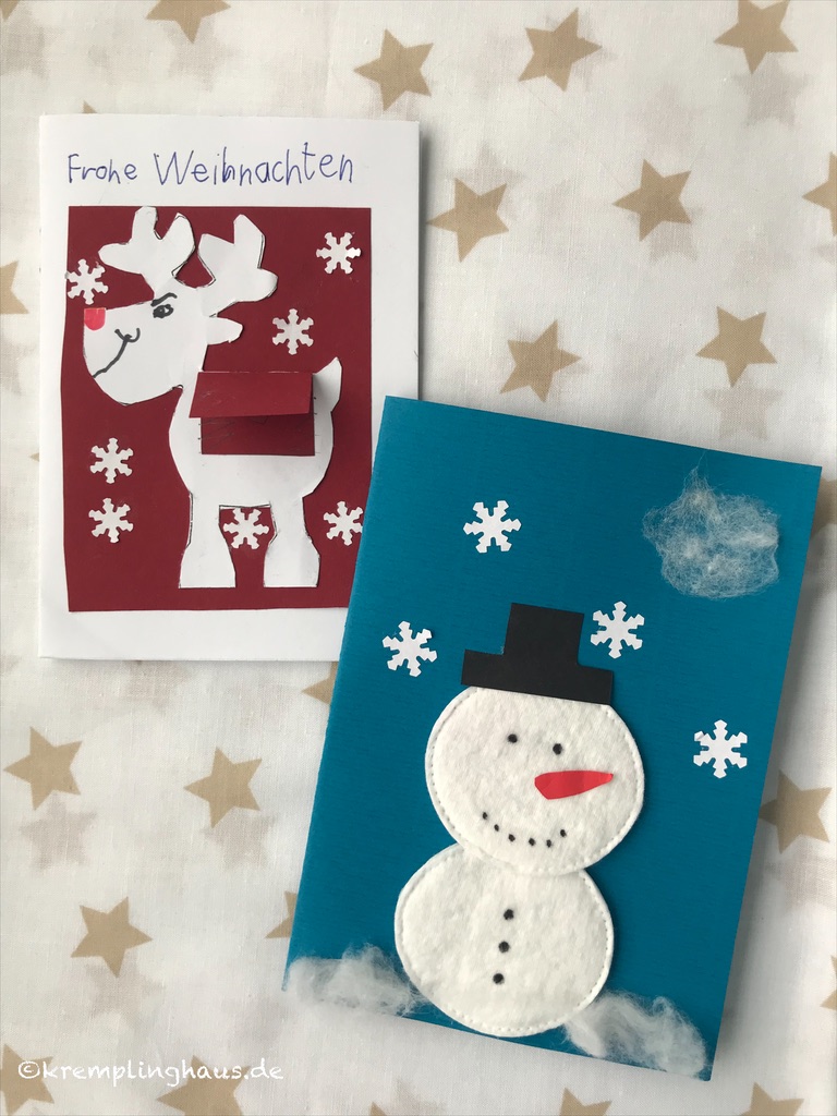 Zwei gebastelte Weihnachtskarten, eine mit Weihnachtselch und Frohe Weihnachten, eine blaue karte mit weißem Schneemann und Schneeflocken