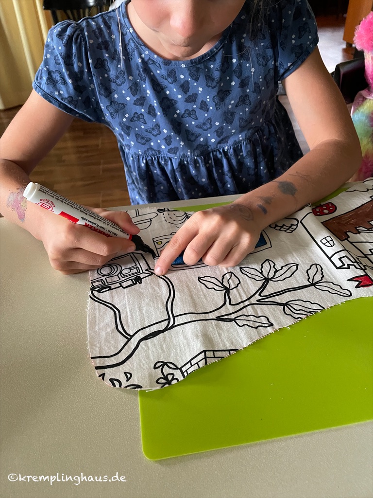 Kind malt mit Stoffstiften auf Stoff